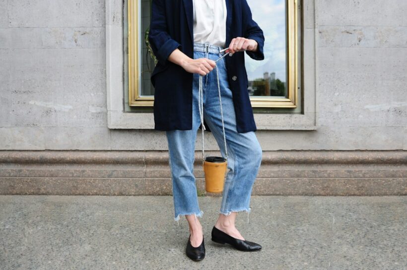 Editorial flat-lay of neutral-toned essentials for a capsule wardrobe for women arranged on a beige background